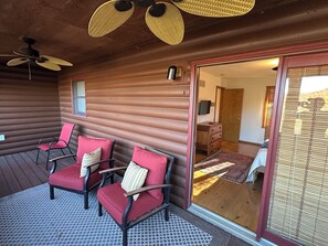 A log cabin interior with a seating area featuring red upholstered chairs with striped pillows, a ceiling fan, and a wooden floor. - Private 4.5-Acre Retreat featuring Hot Tub-Firepit-Walk to Table Rock-Free Daily Attraction Tickets (Lampe)