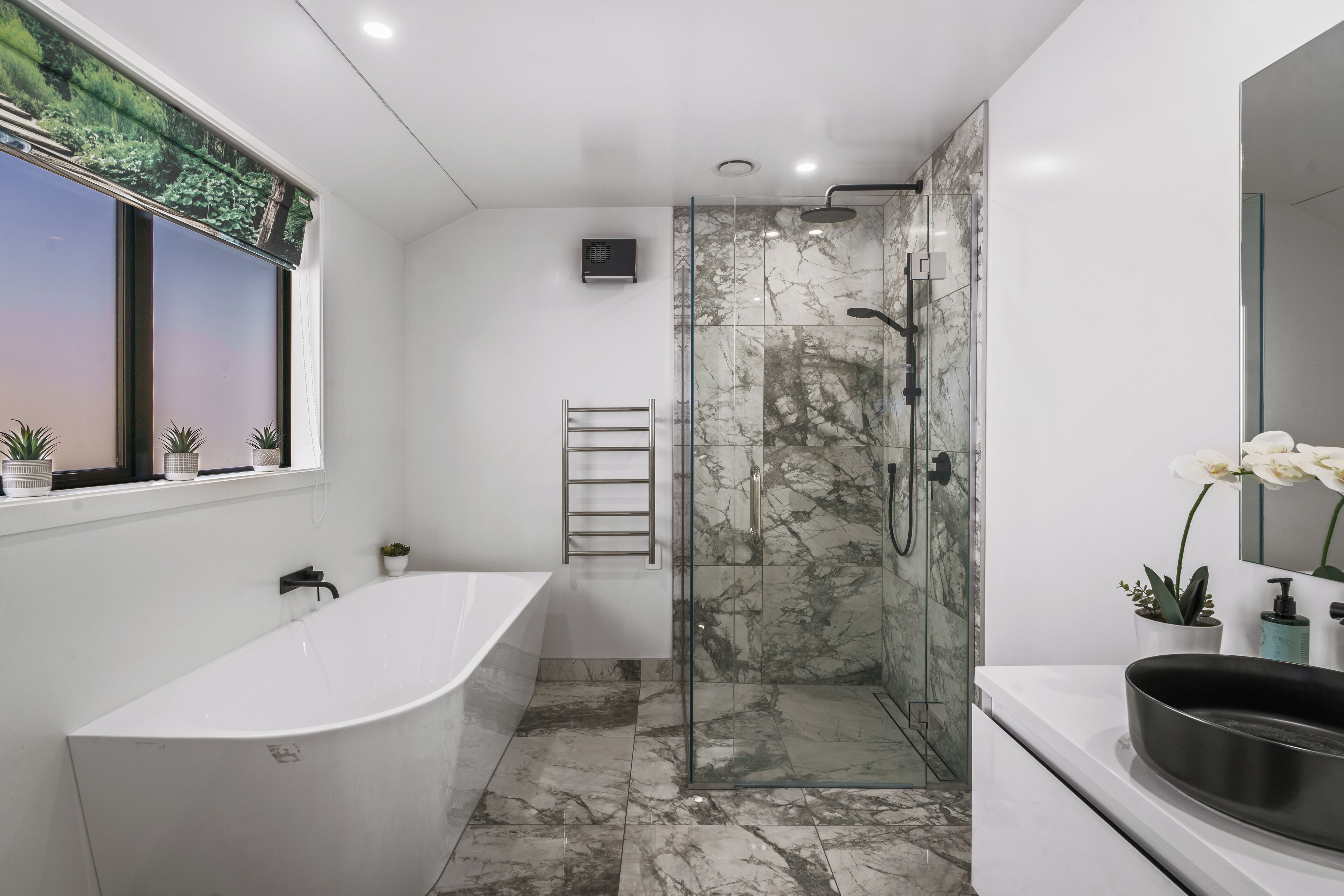 A modern bathroom with a freestanding bathtub, a glass-enclosed shower, and a vanity with a large sink.
