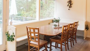 Un comedor con techo de madera, ventanas amplias y una mesa con sillas.