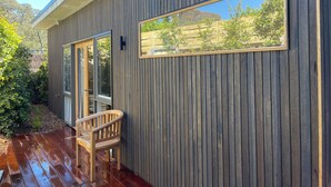 A modern building with a wooden exterior, a deck, and a bench.