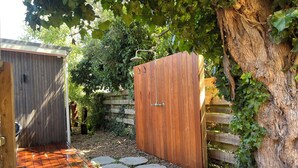 A wooden gate with a metal handle, a wooden fence, and a tree with green leaves.
