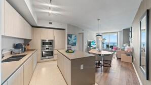 Una cucina moderna con elettrodomestici integrati, un'area pranzo con tavolo rotondo e vista sull'oceano.