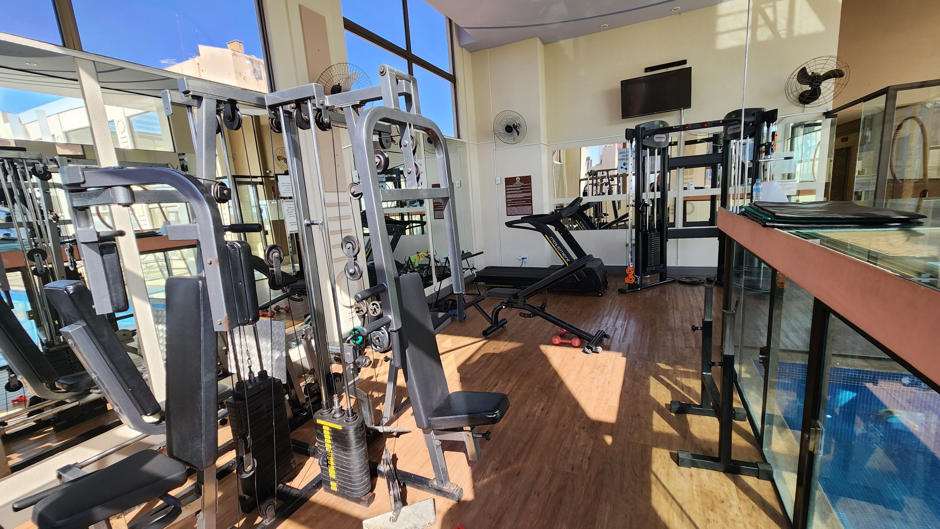 A gym with various exercise equipment, a treadmill, and a mirrored wall.