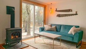 Un salon chaleureux avec une cheminée, un canapé de couleur turquoise et une table basse.