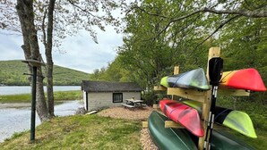 Un chalet au bord du lac, avec des kayaks rangés sur un support en bois.