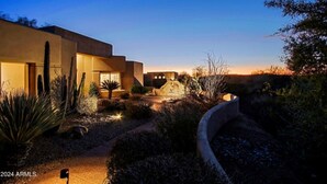Un bâtiment moderne doté d’un jardin aménagé, photographié au crépuscule.