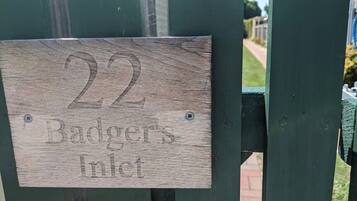 Une plaque en bois portant le numéro 22 et l’inscription « Badger’s Inlet », fixée sur un portail métallique vert.