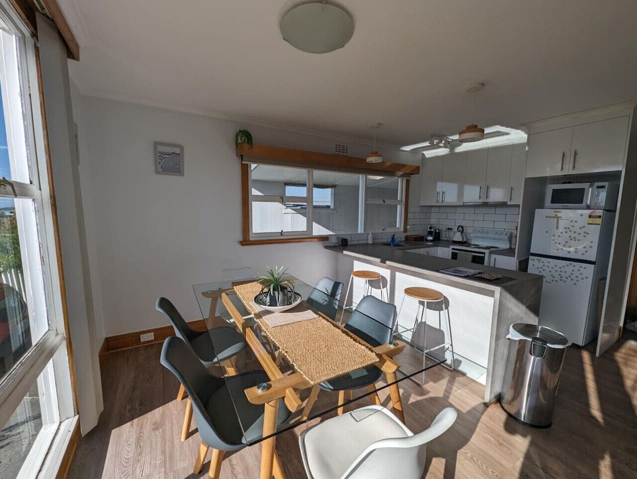 A modern kitchen with a central island, white cabinets, and a stainless steel refrigerator.