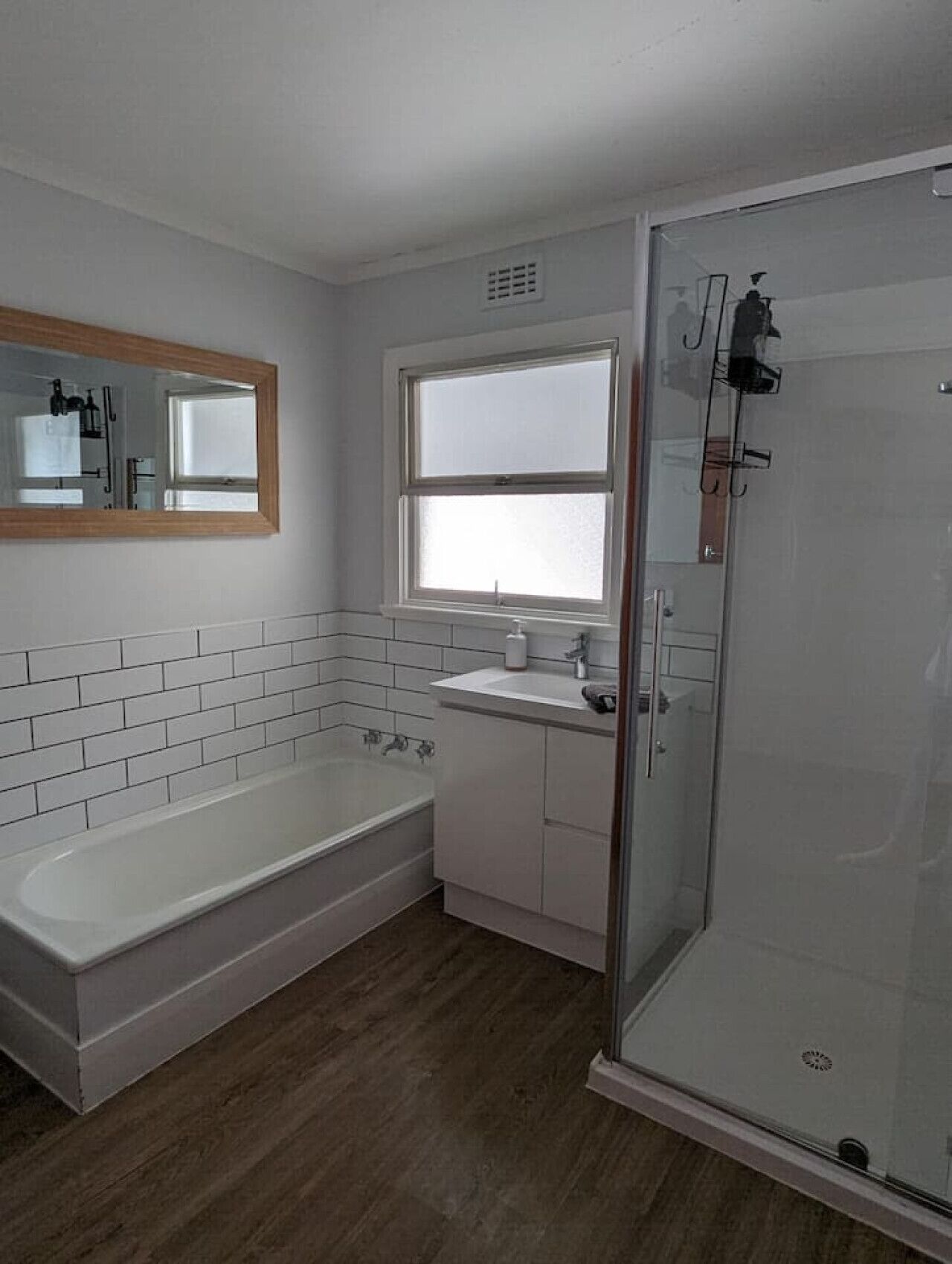 Une salle de bain moderne avec une baignoire, une douche à parois de verre, un lavabo et une fenêtre.