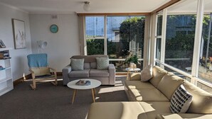 A modern living room with a sofa, armchair, and coffee table. - Spacious Family Home in Devonport  (Devonport)