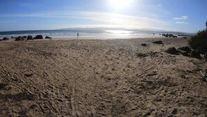A sandy beach with footprints and rocks, a clear sky, and the ocean in the background. - Spacious Family Home in Devonport  (Devonport)