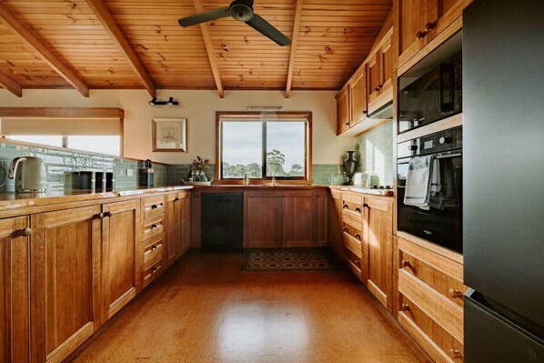 A kitchen with wooden cabinets, a black refrigerator, and a ceiling fan.