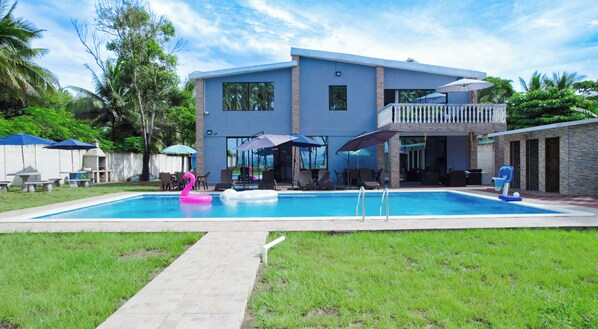 Une maison à deux étages dotée d’une piscine, de mobilier d’extérieur et d’un patio couvert.