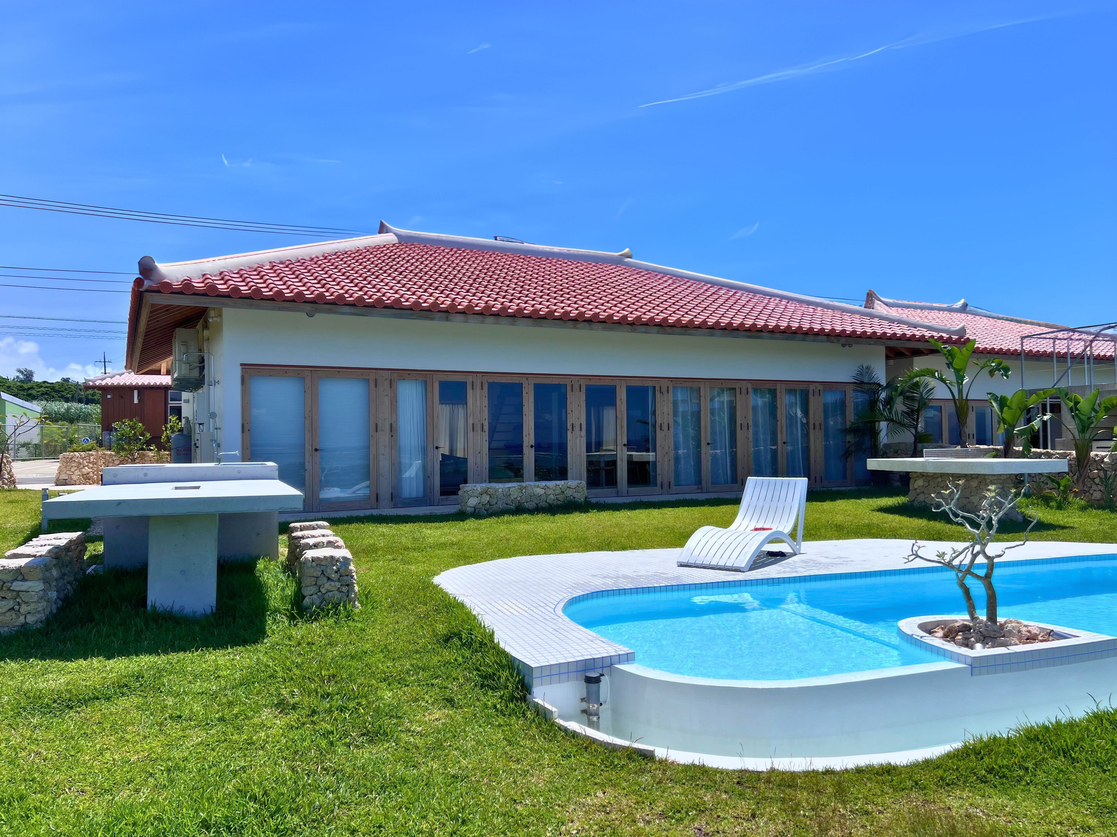 A house with a swimming pool, a covered patio, and a lawn.