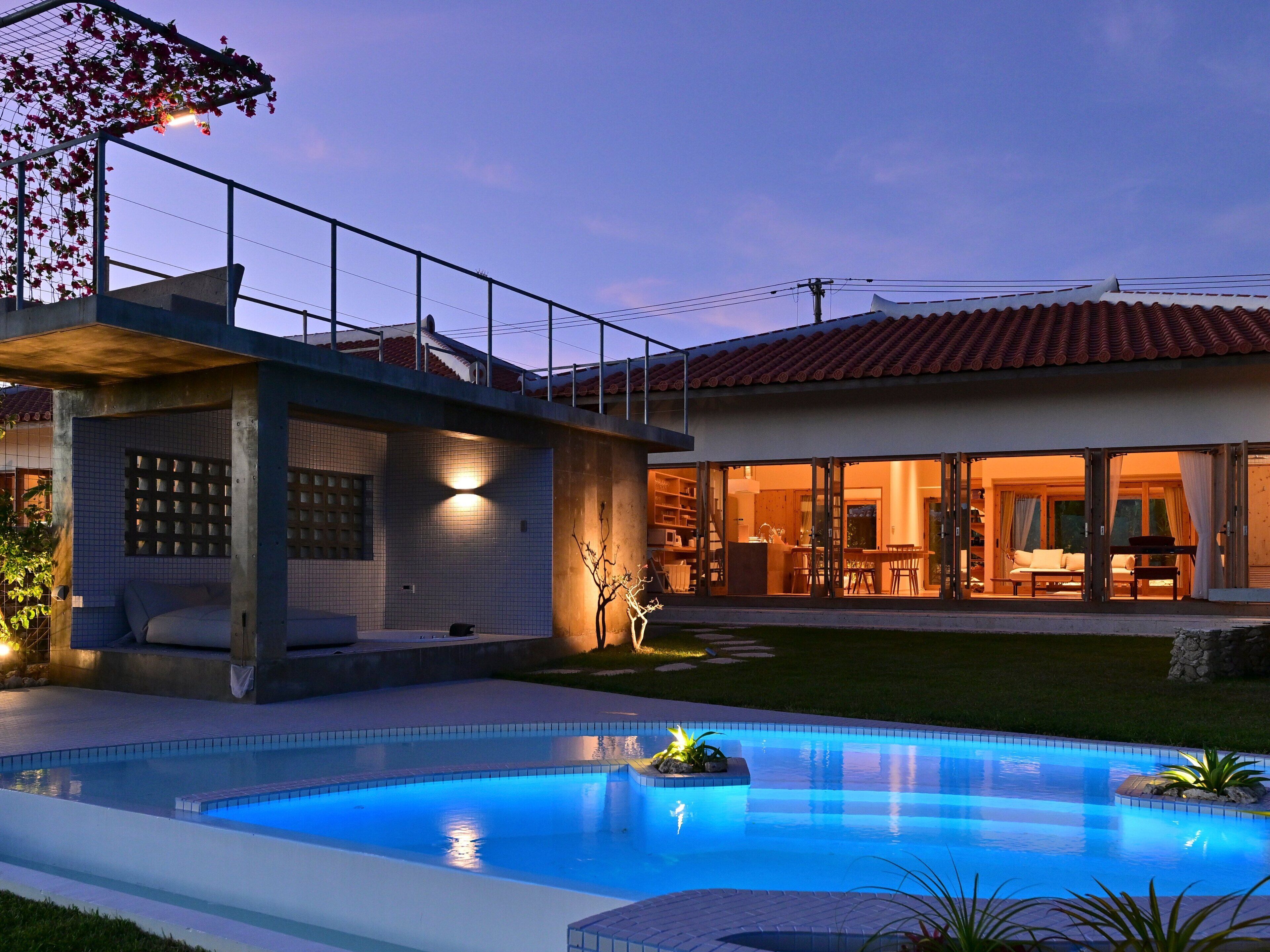 A modern house with a swimming pool, a covered patio, and a large glass door leading to an outdoor dining area.