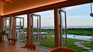 A modern interior with large sliding glass doors leading to a private outdoor area with a pool and garden. - Ishigaki hills (Ishigaki)