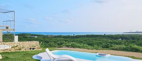 Une piscine avec vue sur la mer et la verdure.