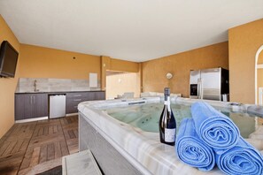 Ein Zimmer mit Whirlpool, einer Weinflasche und Handtüchern.