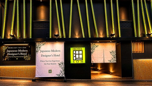 Ein Hotel mit modernem Design, das vertikale Bambuselemente und beleuchtete Beschilderung aufweist.