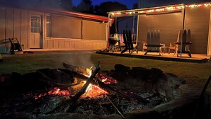 A backyard with a fire pit, a covered patio area with outdoor furniture, and a barbecue grill. - Gibson Getaway- Relax and Unwind (Wagoner)