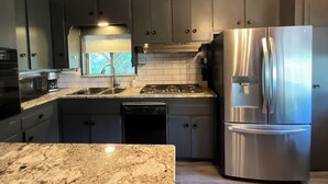 A modern kitchen with dark cabinets, stainless steel appliances, and a granite countertop. - Gibson Getaway- Relax and Unwind (Wagoner)