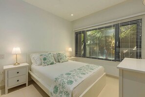 A bedroom with a bed, nightstands, and a window with blinds. - Amazing Waykiri Condo  3 Min to Beach & Marriott (Noord)