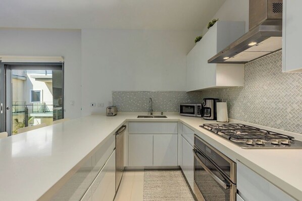 A modern kitchen with a large island, stainless steel appliances, and a herringbone tile backsplash.