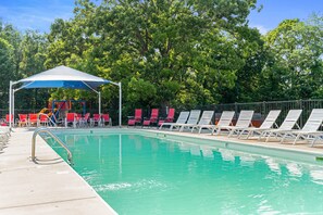 Une piscine avec des chaises longues et un espace ombragé.