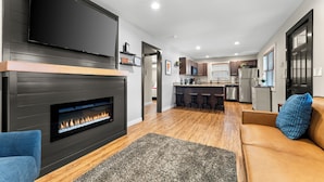 Ein modernes Wohnzimmer mit Kamin, Flachbildfernseher und einer Couch.