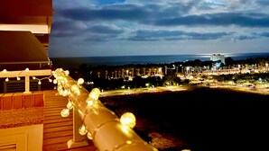 Ein Balkon mit Lichterkette und Blick auf die nächtliche Skyline.