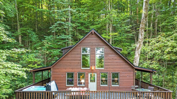 A cabin with a deck, surrounded by dense forest.