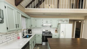 Une cuisine avec des armoires blanches, une cuisinière en acier inoxydable et un plan de travail en bois.