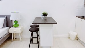 Une cuisine compacte avec un petit îlot central, un plan de travail blanc et un tabouret de bar.