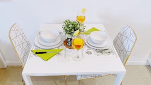 A dining table set with white plates, a glass of orange juice, and a green napkin. - Central Miami Studio w/ Parking - Coconut Grove (Miami)