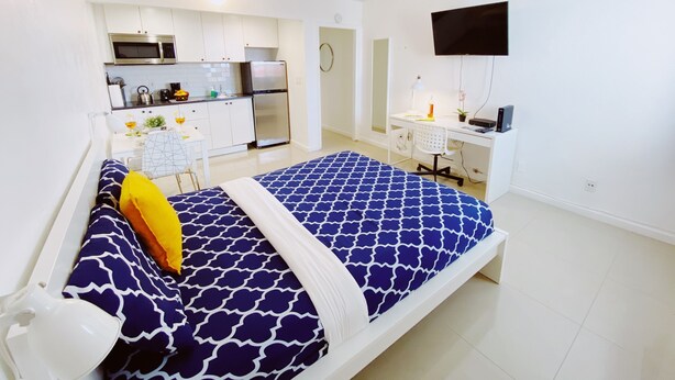 A compact bedroom with a bed, a desk, and a kitchenette. - Central Miami Studio w/ Parking - Coconut Grove (Miami)