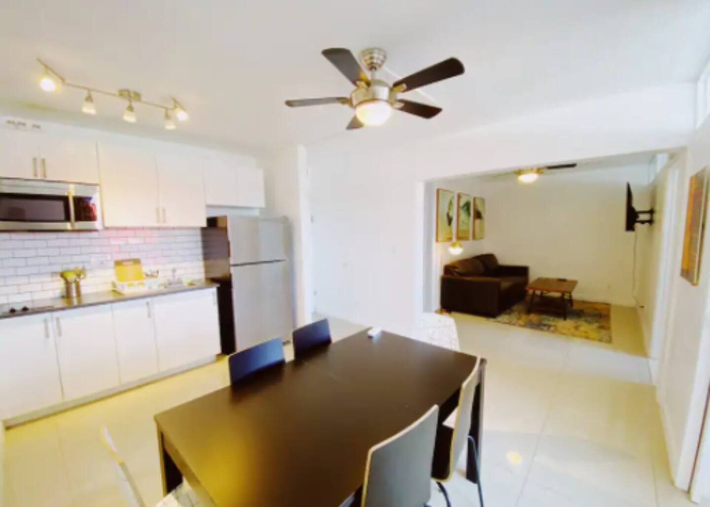 Une cuisine de taille réduite avec des meubles blancs, un four à micro-ondes et un ventilateur de plafond.