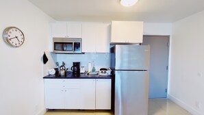 A modern kitchen with white cabinets, a stainless steel refrigerator, a microwave, and a kettle. - Comfy 1-Bedroom Apartment w/ parking - Coconut Grove (Miami)