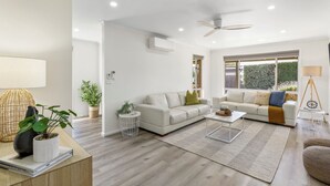 A modern living room with a sofa, coffee table, and a ceiling fan. - 2 Bedroom - Walk to Beach - Pet Friendly (Ocean Grove)