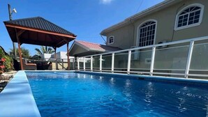 A swimming pool with a covered area and a building with large windows. - Casa Familiar , donde disfrutarás de un relajante alojamiento. (Tela)
