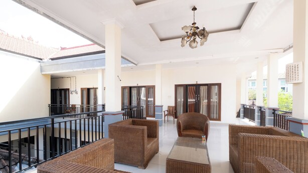 A spacious balcony with wicker furniture, a ceiling fan, and a view of the building's exterior. - Samudra Homestay (Kuta)