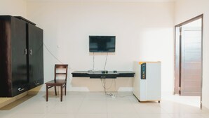 A room with a desk, chair, wardrobe, television, and a refrigerator. - Samudra Homestay (Kuta)