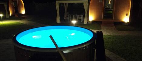 A swimming pool with a diving board, surrounded by wooden structures with lights.