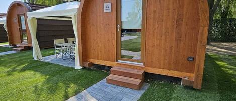 Una cabaña de madera con entrada curvada y un pequeño porche.