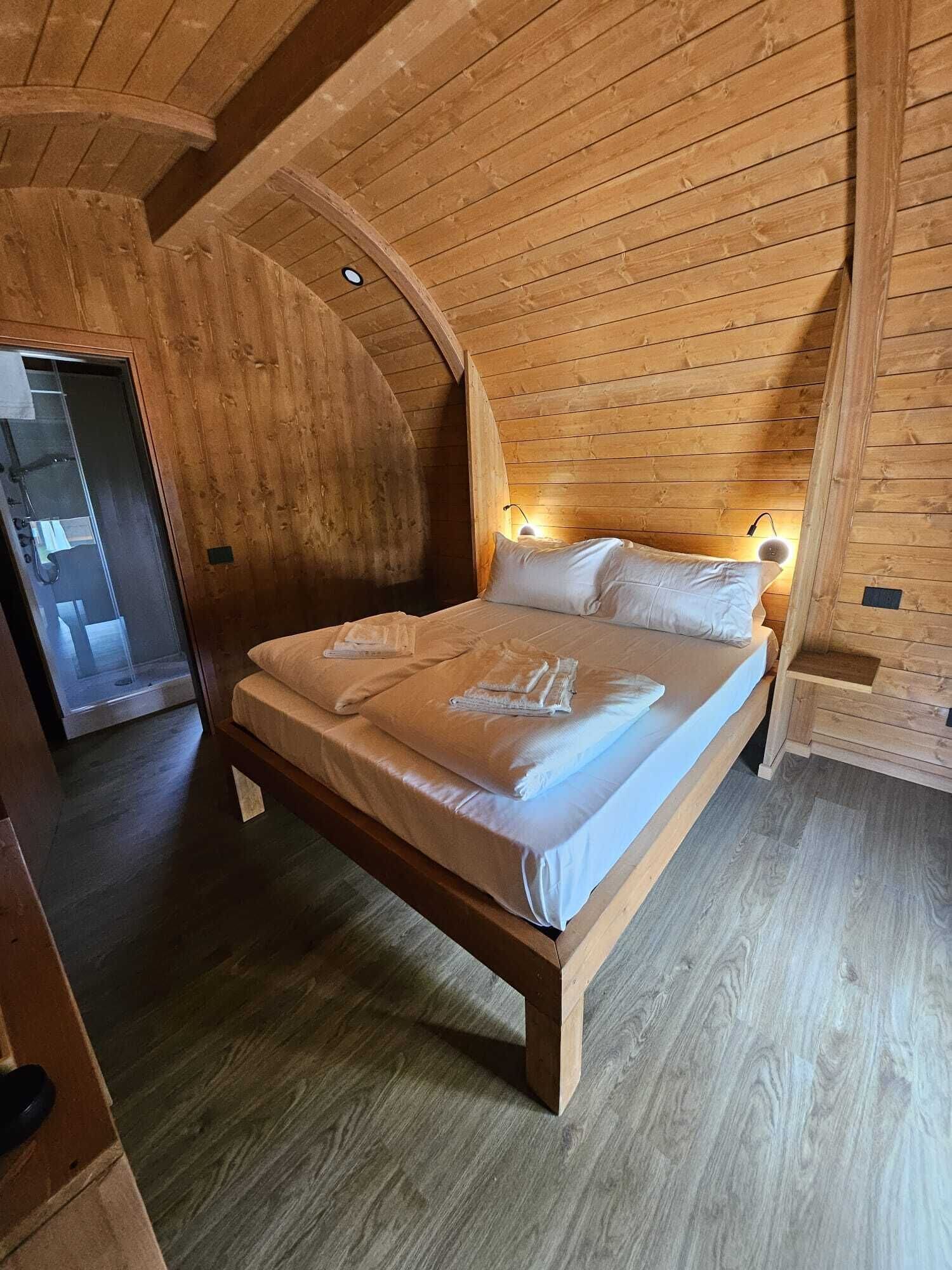 A wooden loft bedroom with a bed, wooden walls, and a sloped ceiling.