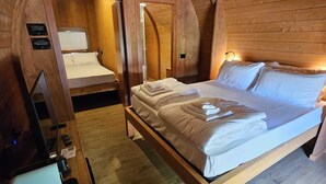 A cozy attic bedroom with a wooden ceiling, a large bed, a desk, and a chair. - VICOLUNGO Glamor Lodge & Spa Ondaland waterpark (Vicolungo)