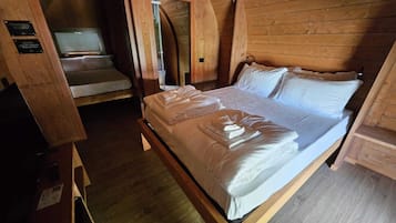 A wooden room with a bed, a small table, and a bench.