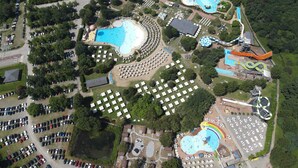 An aerial view of a theme park with multiple water slides, pools, and a large parking area. - VICOLUNGO Glamor Lodge & Spa Ondaland waterpark (Vicolungo)