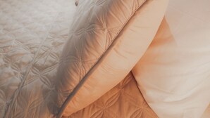 Una cama con cubrecama acolchado y una ventana encima.