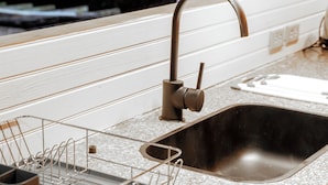 Una cocina con un lavamanos de acero inoxidable, un escurreplatos y una encimera de madera.
