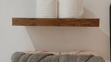 Two wooden shelves with rolled towels, one white and one gray.